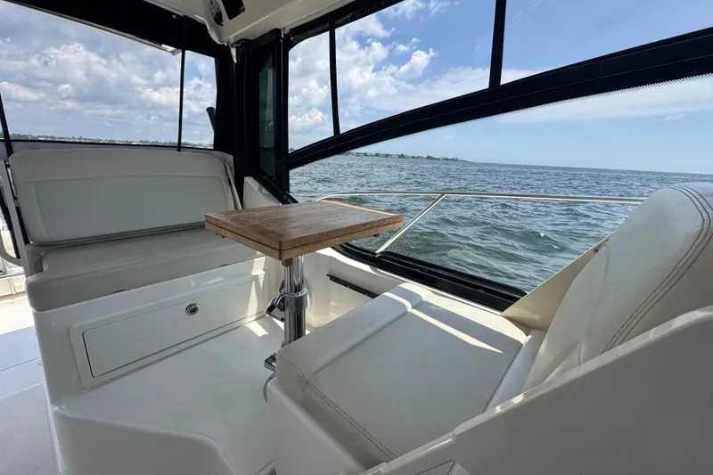 Slide: The Image of 2023 Boston Whaler 325 Conquest interior with seating and table, overlooking the ocean. - 18