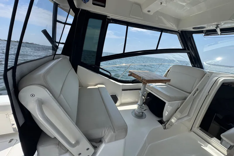 Slide: The Image of 2023 Boston Whaler 325 Conquest interior with seating and table, overlooking the ocean. - 17