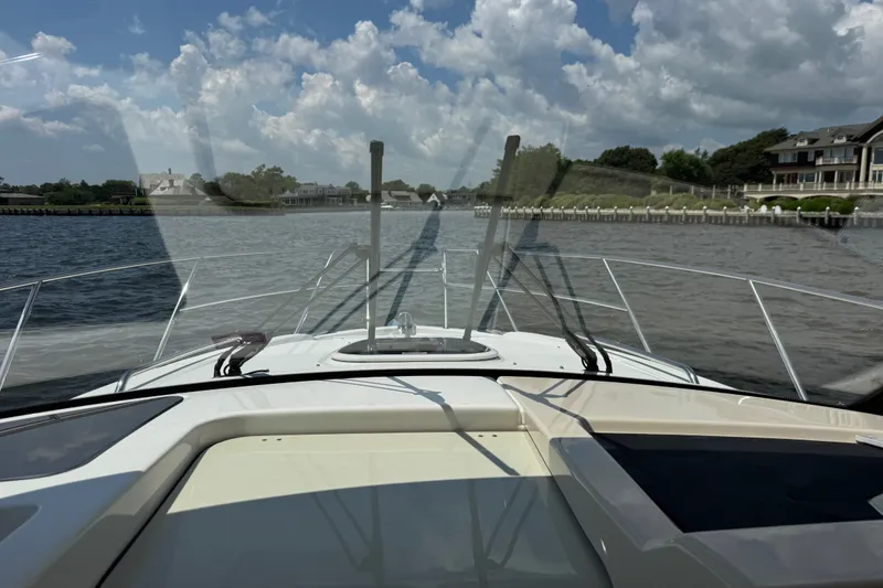 Slide: The Image of 2023 Boston Whaler 325 Conquest cruising on a scenic waterway under a partly cloudy sky. - 26