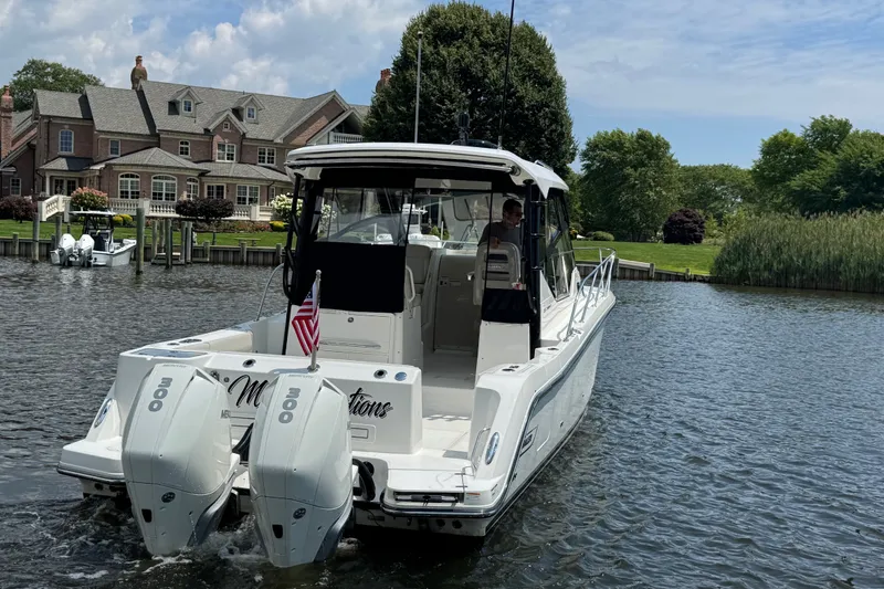 Slide: The Image of 2023 Boston Whaler 325 Conquest boat on a scenic waterway near luxury homes. - 3