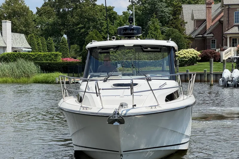 Slide: The Image of 2023 Boston Whaler 325 Conquest boat on a scenic waterway near luxury homes. - 5
