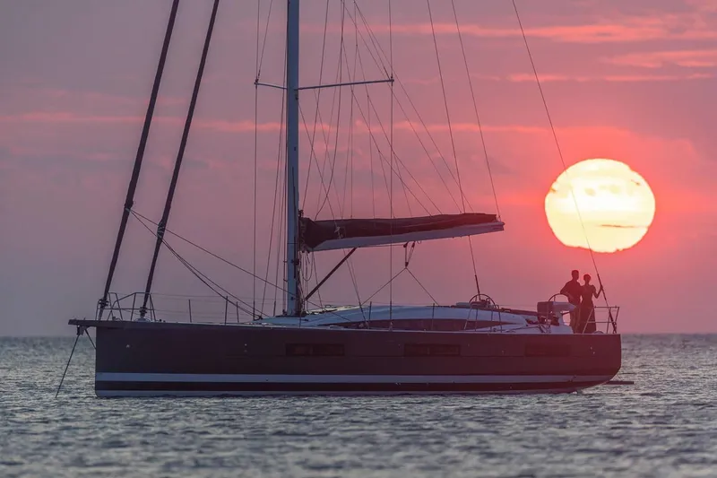 Slide: The Image of Manufacturer Provided Image: 2025 Jeanneau 60 yacht sailing at sunset with silhouetted figures on deck. - 5