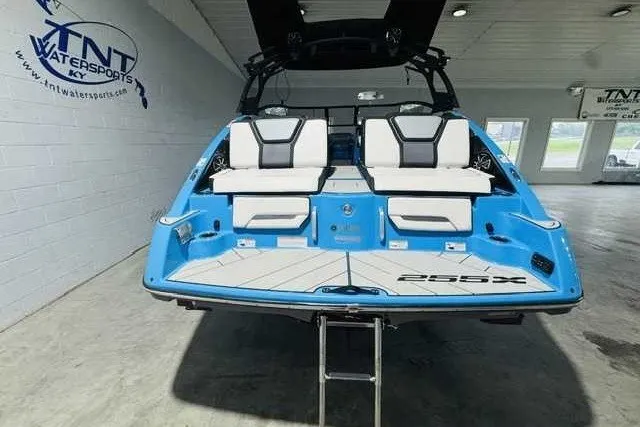 Slide: The Image of 2022 Yamaha Boats 255XD in showroom, featuring sleek blue design and comfortable seating. - 2