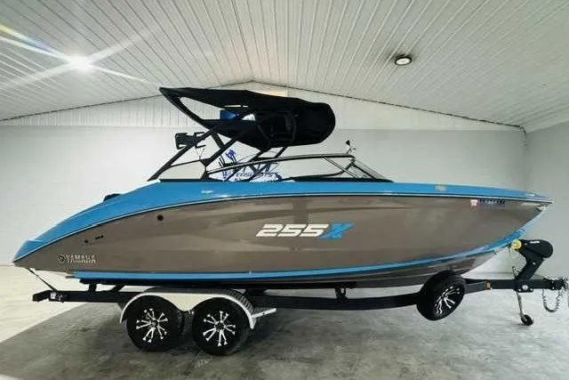 The Image of 2022 Yamaha Boats 255XD in showroom, blue and gray design on trailer. - 1