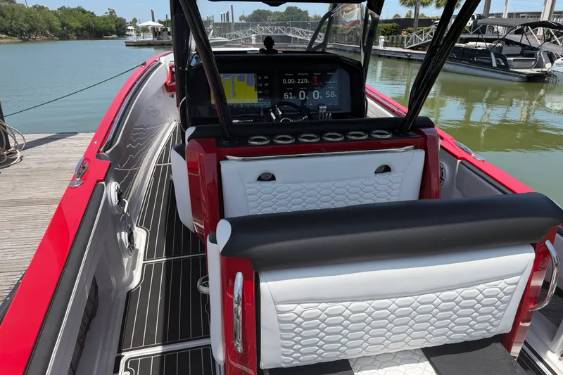 Slide: The Image of 2024 Nor-Tech 390 Sport boat interior with red and white seating, docked by the water. - 47