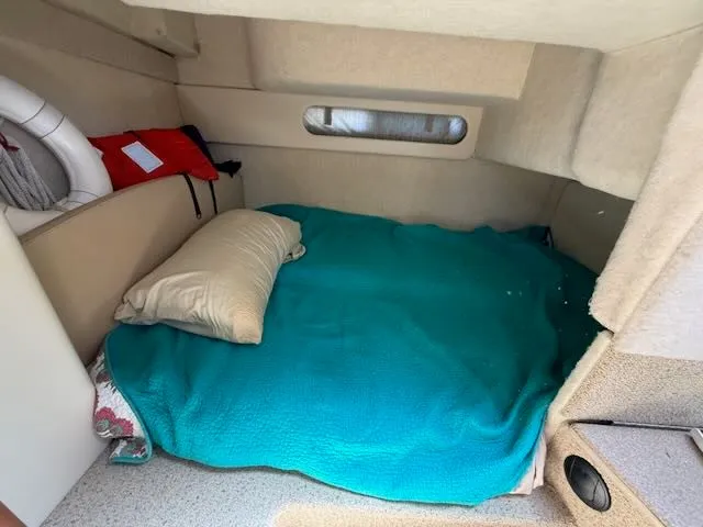 Slide: The Image of The cabin of a 2004 Bayliner 305SB features a cozy bed with a turquoise blanket. - 27