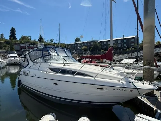 The Image of A white 2004 Bayliner 305SB is docked in the water, surrounded by other boats. - 0