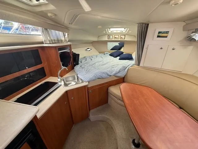 Slide: The Image of Interior of a 2004 Bayliner 305SB with cozy bed, kitchenette, and seating area. - 23