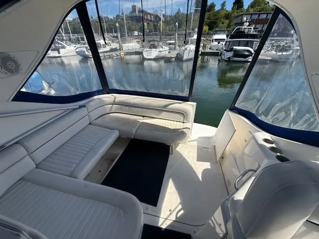 Slide: The Image of Interior of a 2004 Bayliner 305SB with white seating and a view of the marina. - 8