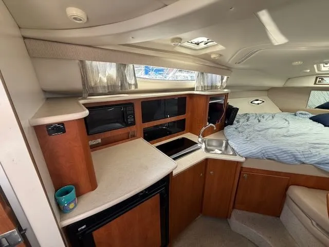 Slide: The Image of Interior of a 2004 Bayliner 305SB featuring a kitchen and sleeping area. - 24