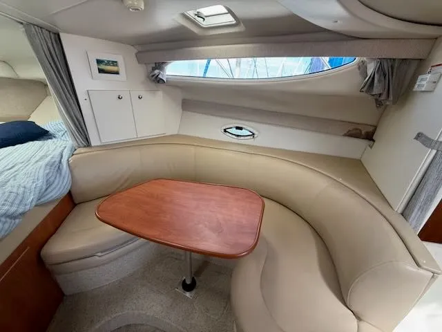 Slide: The Image of Interior of the 2004 Bayliner 305SB featuring a cozy seating area and a wooden table. - 25