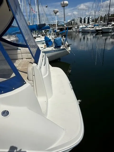 Slide: The Image of A 2004 Bayliner 305SB docked in a marina. Other boats are visible in the background. - 2