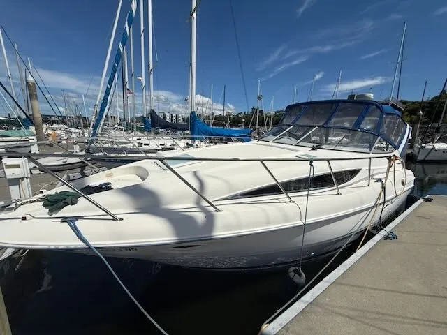 Slide: The Image of A 2004 Bayliner 305SB docked on a sunny day, surrounded by other boats in the marina. - 1