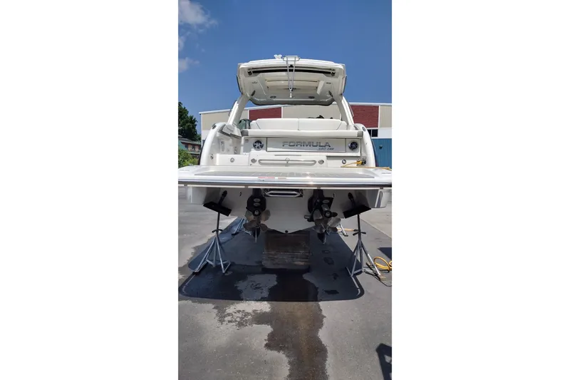 Slide: The Image of 2026 Formula 350 Crossover Bowrider boat, rear view, on stands, outdoors. - 13