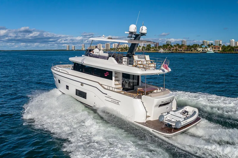 Slide: The Image of 2023 Sirena Flybridge yacht cruising on blue ocean near city skyline. - 2