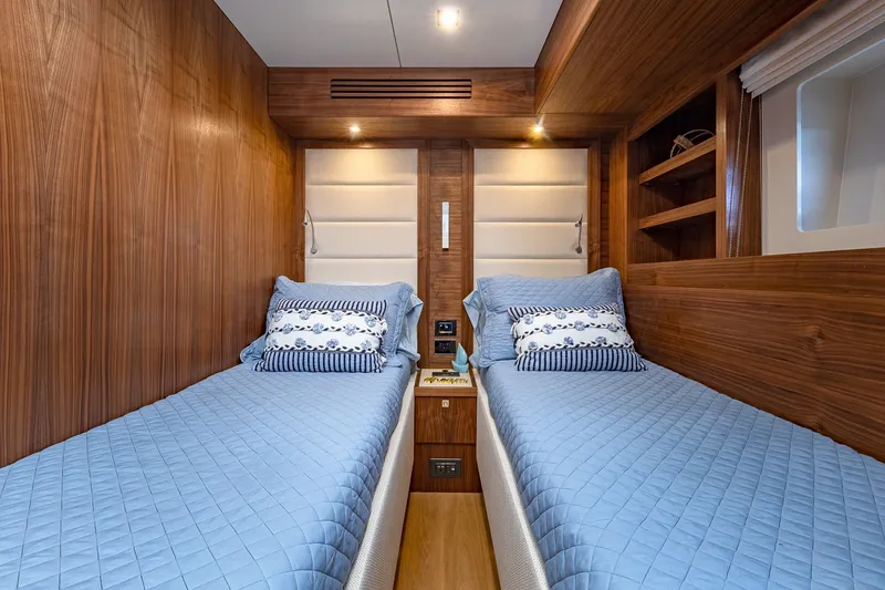 Slide: The Image of Luxurious twin cabin interior on 2023 Sirena Flybridge yacht with wood paneling and blue bedding. - 55