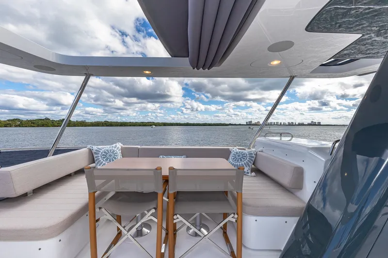 Slide: The Image of 2023 Sirena Flybridge yacht with elegant seating, table, and scenic water view. - 28