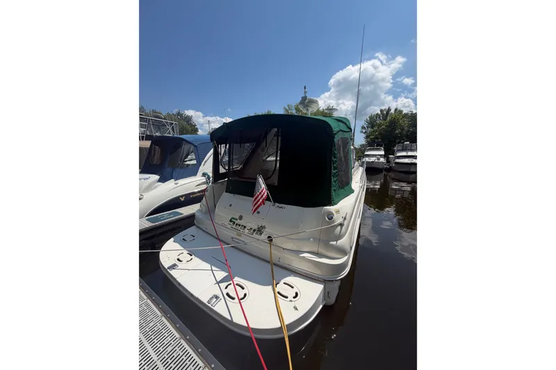 Slide: The Image of 2000 Sea Ray 340 Sundancer docked, featuring green canopy and American flag. - 2