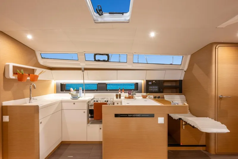Slide: The Image of The interior of the Jeanneau Sun Odyssey 455 features a modern kitchen with wood paneling and large windows. - 6