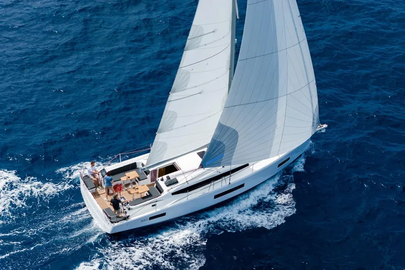 The Image of The Jeanneau Sun Odyssey 455 sails on open water with full sails and crew on deck. - 0