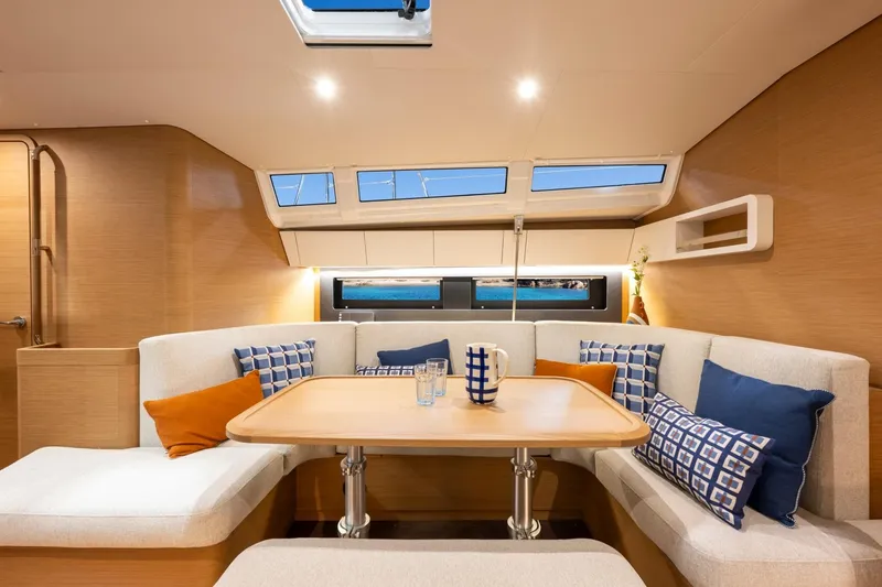 Slide: The Image of The interior of the 2026 Jeanneau Sun Odyssey 455 features a cozy seating area with cushions and a table. - 9