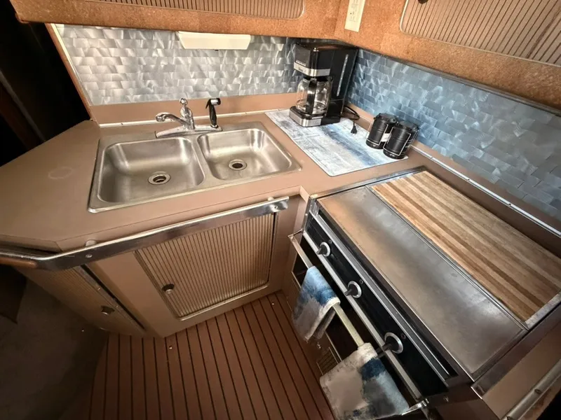 Slide: The Image of The galley of a 1981 Sea Ray 360 Sportfish with a sink, stove, and coffee maker. - 34