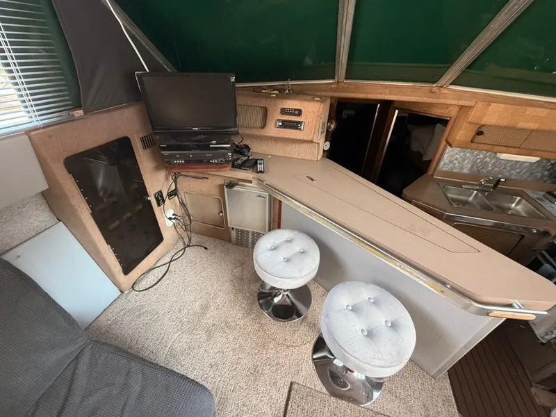 Slide: The Image of Interior of a 1981 Sea Ray 360 Sportfish with a bar, stools, and a TV. - 23