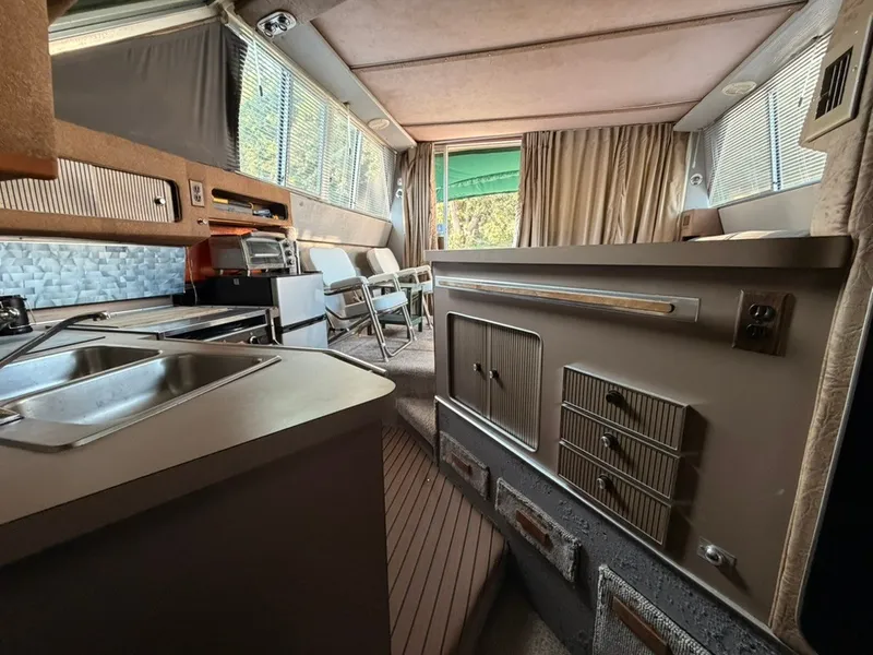 Slide: The Image of Interior of a 1981 Sea Ray 360 Sportfish featuring a kitchen and seating area. - 14