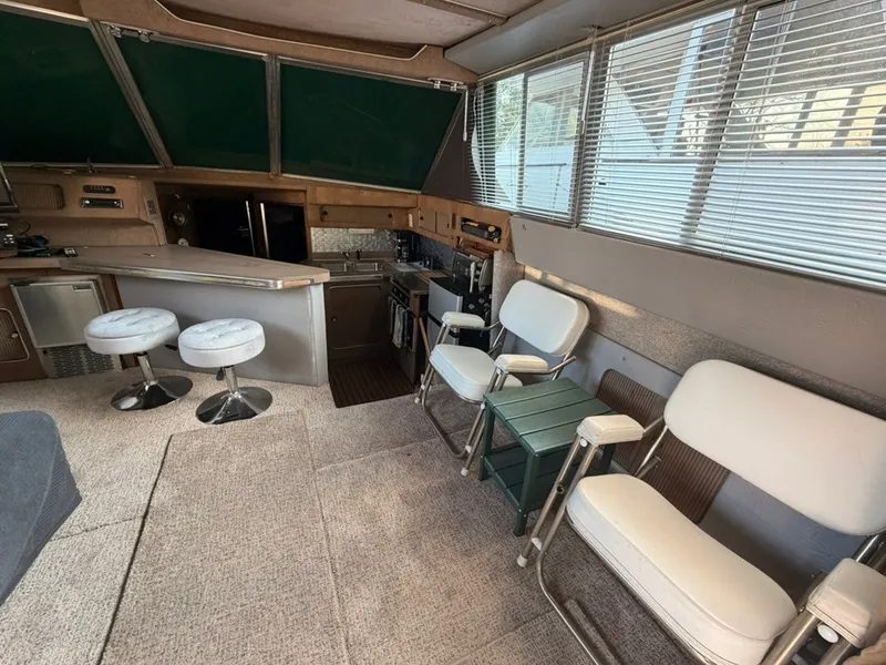 Slide: The Image of Interior of a 1981 Sea Ray 360 Sportfish with bar stools and cushioned chairs. - 17