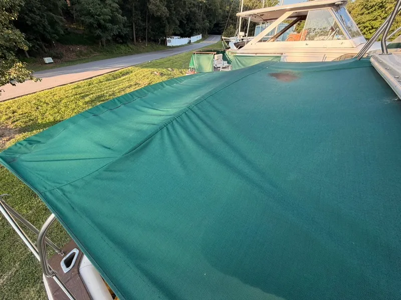 Slide: The Image of A green boat cover on a 1981 Sea Ray 360 Sportfish, parked beside a road. - 29
