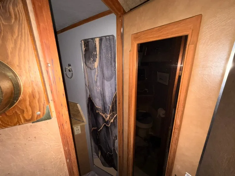 Slide: The Image of Interior of a 1981 Sea Ray 360 Sportfish with wooden doors and a small bathroom. - 37