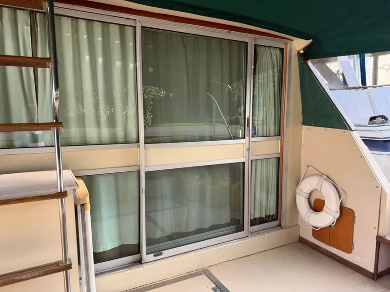 Slide: The Image of The image shows the aft deck of a 1981 Sea Ray 360 Sportfish with a sliding glass door and curtains. - 13
