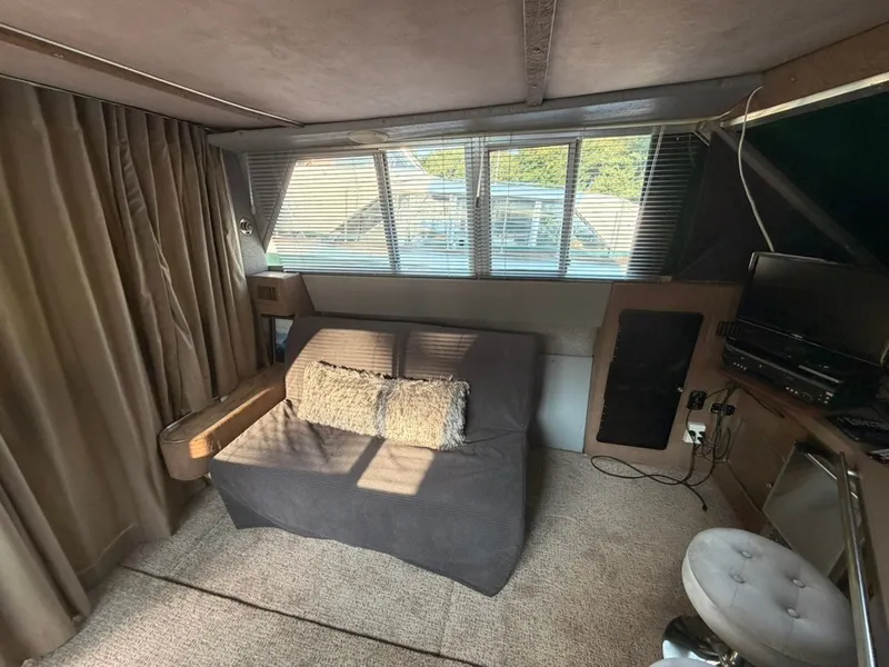 Slide: The Image of Interior of a 1981 Sea Ray 360 Sportfish with a sofa, carpeted floor, and windows with blinds. - 26