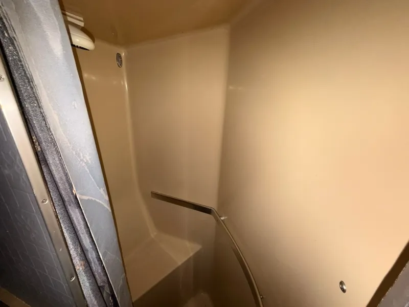 Slide: The Image of The shower stall on a 1981 Sea Ray 360 Sportfish boat, featuring beige walls and a bench. - 45