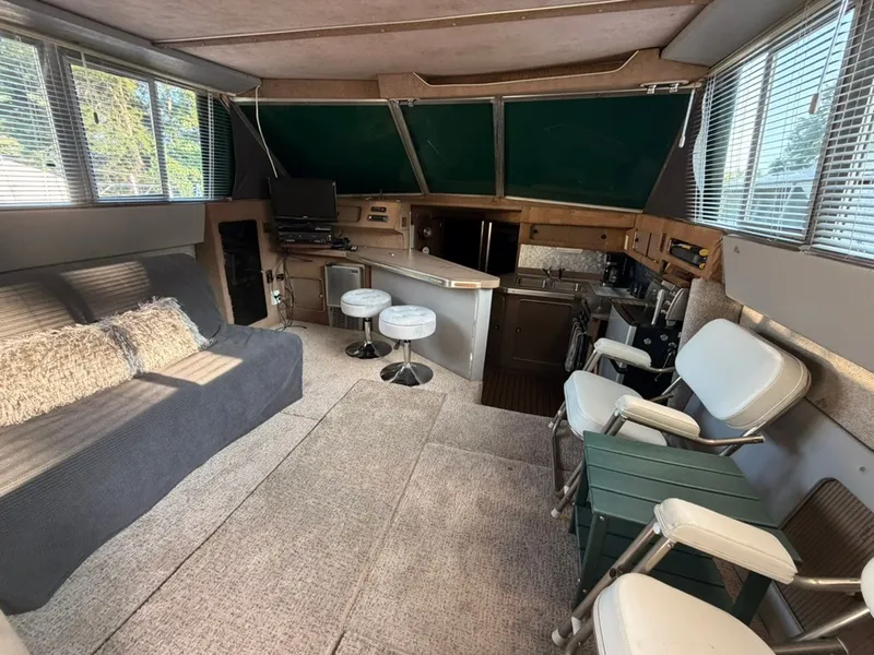Slide: The Image of Interior of the 1981 Sea Ray 360 Sportfish with sofa, bar stools, and helm area. - 29