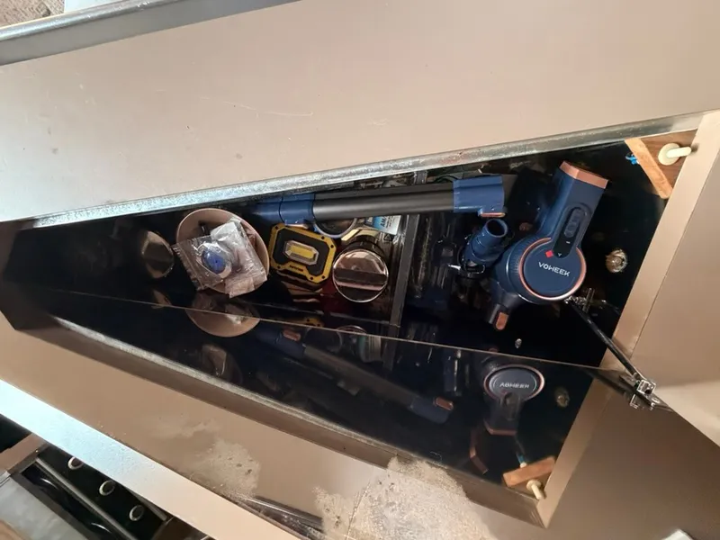 Slide: The Image of An open storage compartment on a boat reveals tools and equipment, including a flashlight and tape measure. - 35