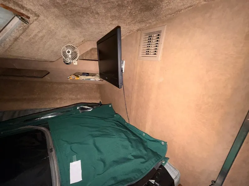 Slide: The Image of The interior of a 1981 Sea Ray 360 Sportfish features a green cover and a mounted screen. - 40