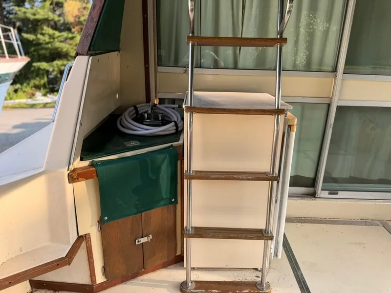 Slide: The Image of A ladder with wooden steps leads to an elevated area on a boat. A green cloth covers a storage space. - 31
