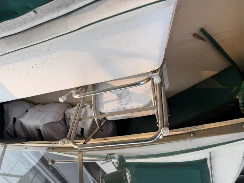 Slide: The Image of A metal folding chair on a boat with green covers and white cushions. - 24
