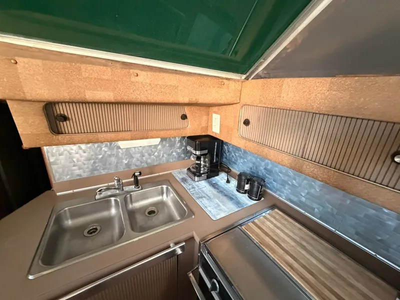 Slide: The Image of The galley of a 1981 Sea Ray 360 Sportfish with a sink, coffee maker, and countertop. - 48