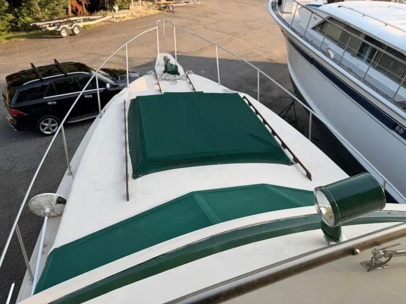 Slide: The Image of A 1981 Sea Ray 360 Sportfish with green covers on the deck, parked next to a car. - 20