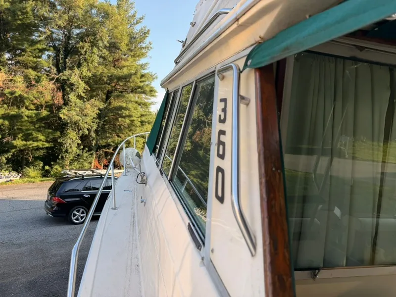 Slide: The Image of A 1981 Sea Ray 360 Sportfish with a green canopy, parked next to a car. - 32