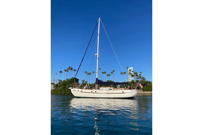 The Image of Vintage 1976 CT 48 sailboat on calm water, clear blue sky, palm trees in background. - 1