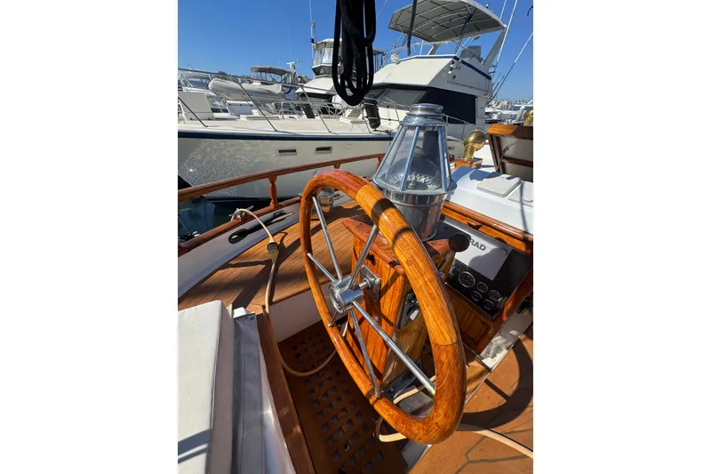 Slide: The Image of Wooden steering wheel on a 1976 CT 48 yacht, docked with other boats. - 25