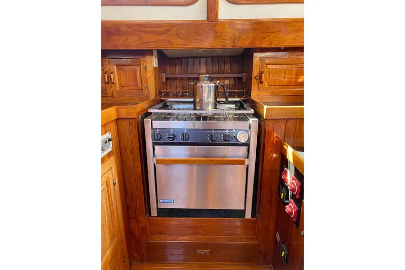 Slide: The Image of Vintage 1976 CT 48 yacht kitchen with stainless steel stove and wooden cabinetry. - 19