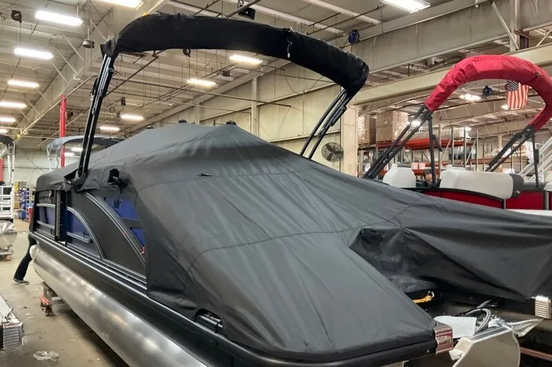 Slide: The Image of 2027 Bennington 23 M Swingback pontoon boat with black cover in a warehouse setting. - 18