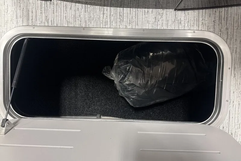 Slide: The Image of Storage compartment of 2027 Bennington 23 M Swingback with a black bag inside. - 20