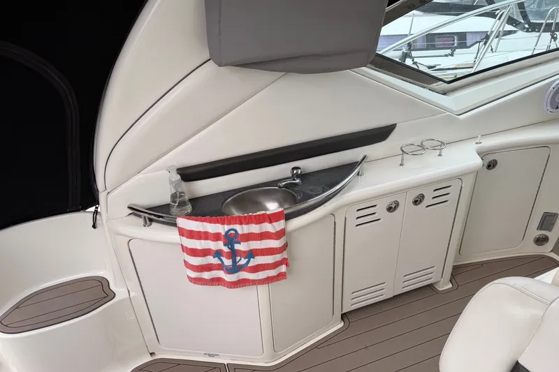 Slide: The Image of 2005 Sea Ray 420 Sundancer yacht interior with sink, striped towel, and storage cabinets. - 13