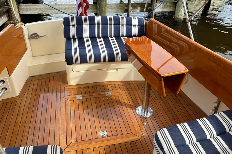Slide: The Image of Hinckley Picnic Boat 37 MKIII 2014 interior with striped seating and polished wood table. - 15