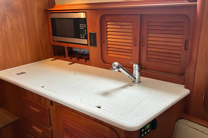 Slide: The Image of Hinckley Picnic Boat 37 MKIII 2014 galley with microwave, sink, and wooden cabinetry. - 34